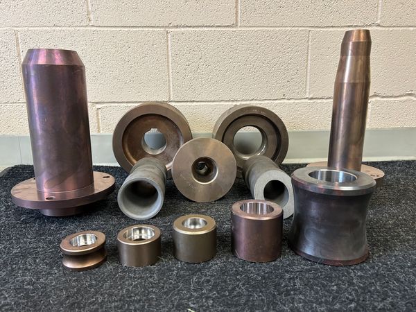 A collection of cylindrical metal machine parts arranged on a carpet.