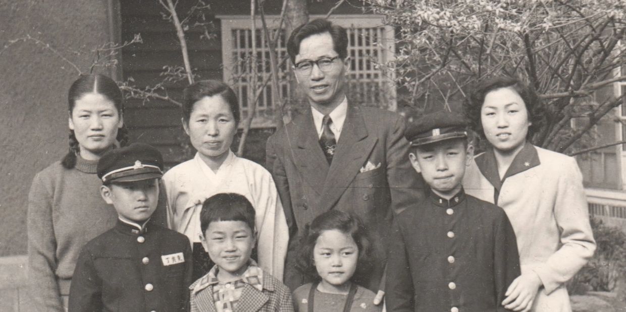 A formal black-and-white family portrait with adults and children in traditional and school attire.