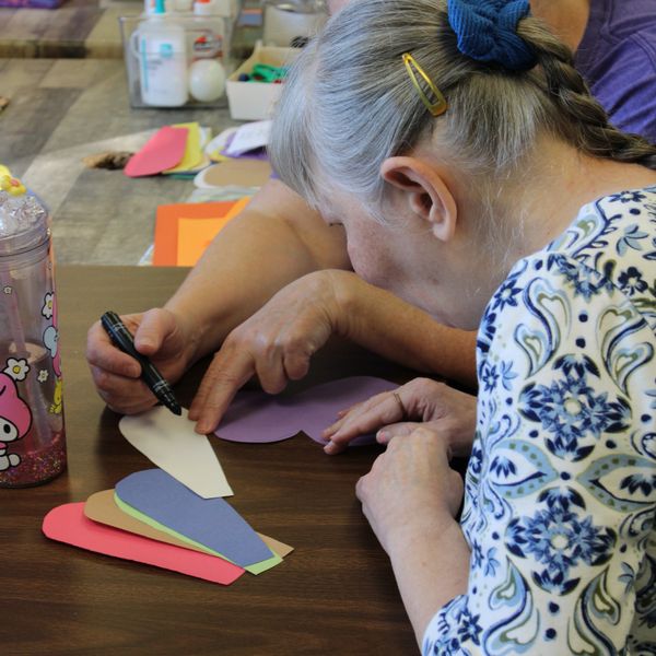 Two women crafting with colorful paper hearts.