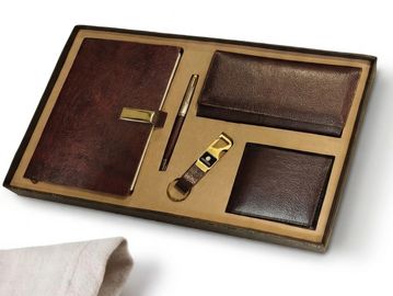 Elegant brown leather gift set with notebook, pen, wallets, and keychain.