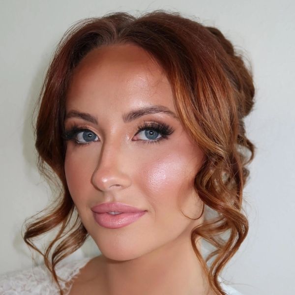 Close-up of a woman with blue eyes and curly auburn hair.
