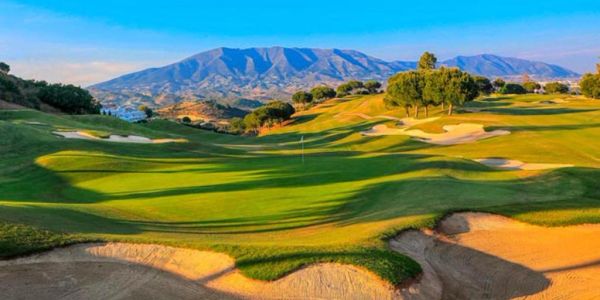 Campo de golf con montañas al fondo.