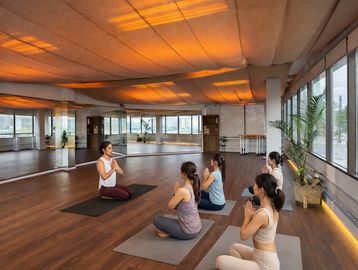 A yoga instructor leads a class of five women in meditation in a spacious studio.