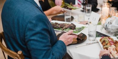 Person serving steak at a dinner table.