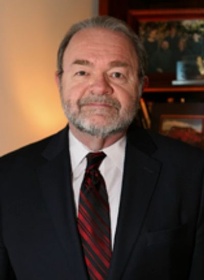 Man in a suit and tie posing indoors with warm lighting.
