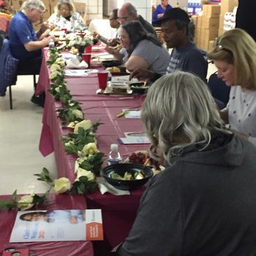 People eating at a decorated table with flowers and food.