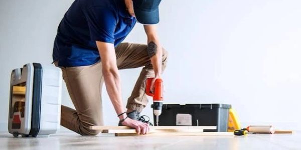 Person assembling furniture using a drill.