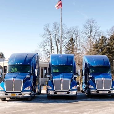 Lineup of Sandell Transport trucks in front of the building.