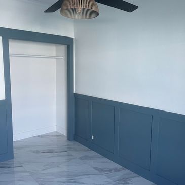 Empty room with blue half-wall paneling and marble floor.