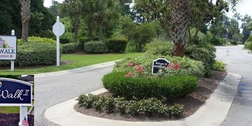 Entrance to a residential community with landscaped greenery and signage.