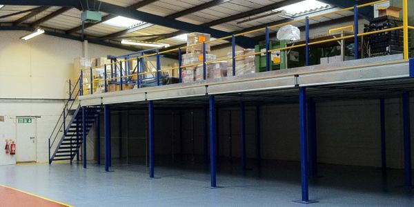 Warehouse mezzanine floor with stacked boxes and storage containers.
