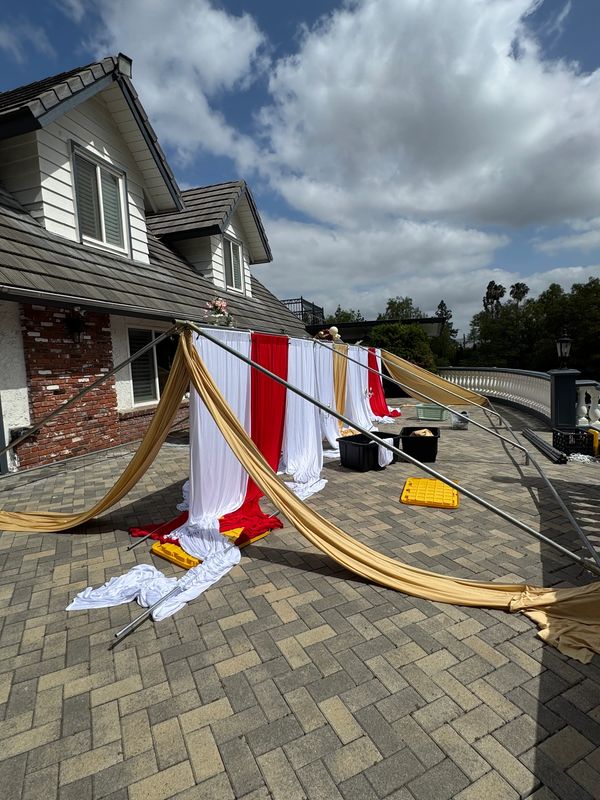 Setting up a tent with draping in red and white and gold colors size 20x30.