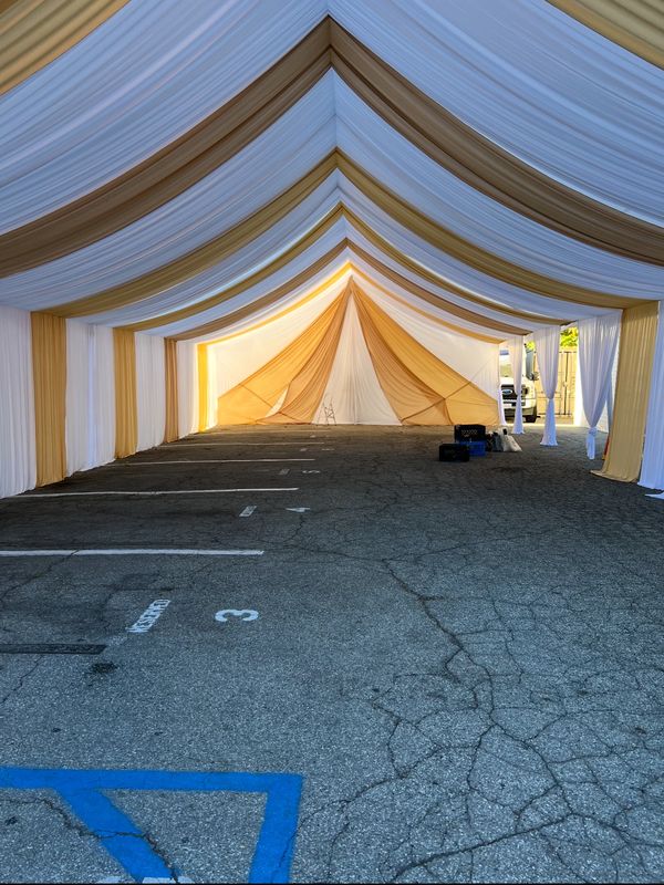 30x30 Party tent white and gold draping. White chairs and 5' round tables. Red Runners. Tablecloths.