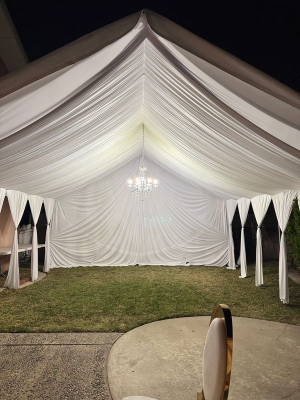 20x20 Tent with white draping fabrics and a chandelier. 