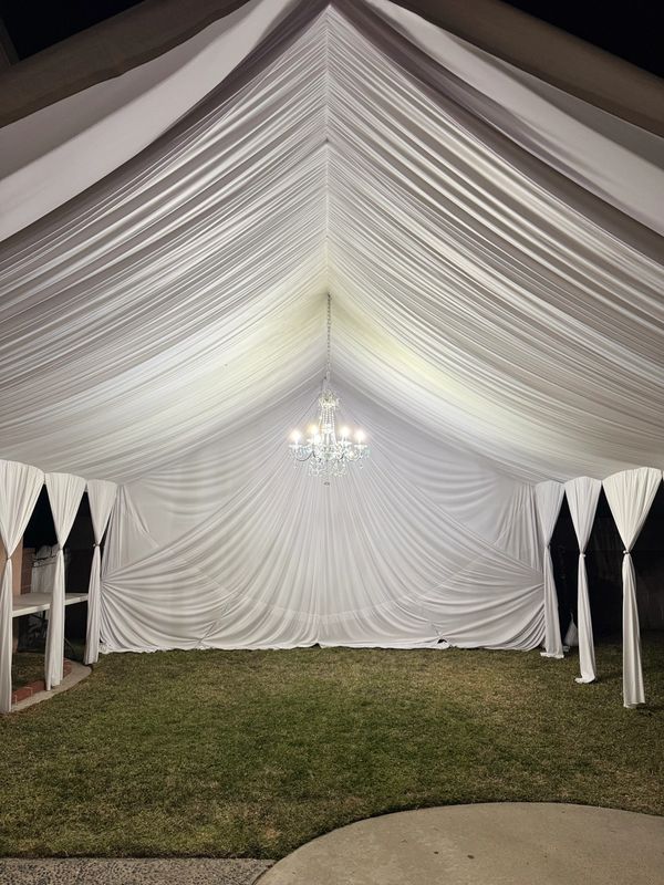 20x20 Tent with white draping fabrics and a chandelier. 