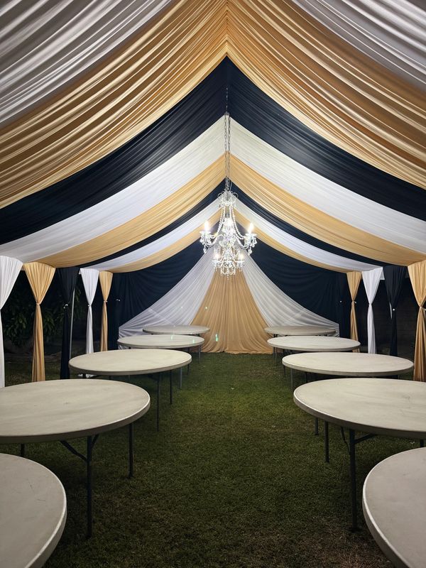 Party tent size 20x30 draped in black white and gold. Chandeliers included. 5' round tables.