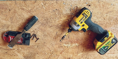 A cordless drill and a set of screws on a wooden surface.