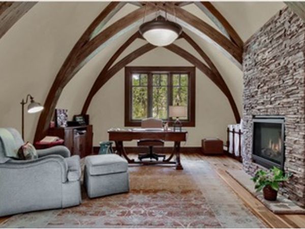 Cozy home office with vaulted wooden ceilings and stone fireplace.