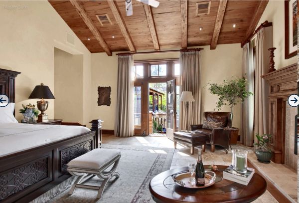 Cozy bedroom with wooden ceiling and door to balcony.