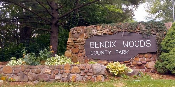 Entrance sign for Bendix Woods County Park surrounded by greenery.