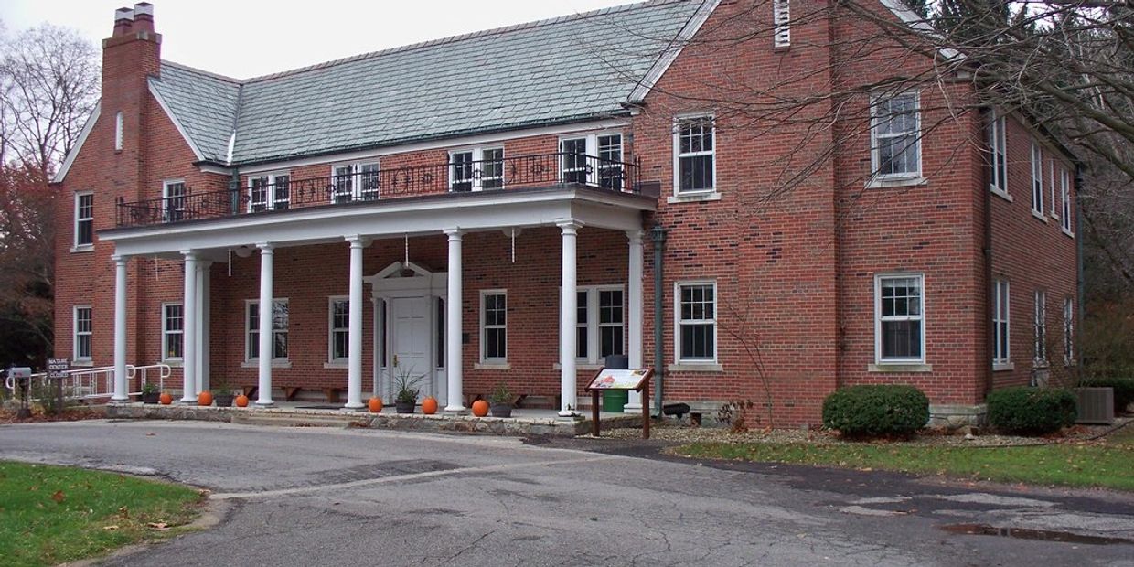 Large brick building with white columns and pumpkins on the porch.