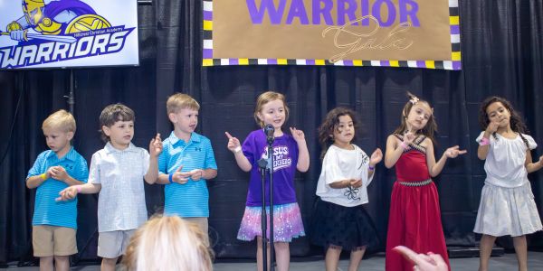 Children performing on stage in colorful outfits.