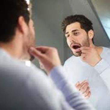Man examining his skin in the mirror with concern.