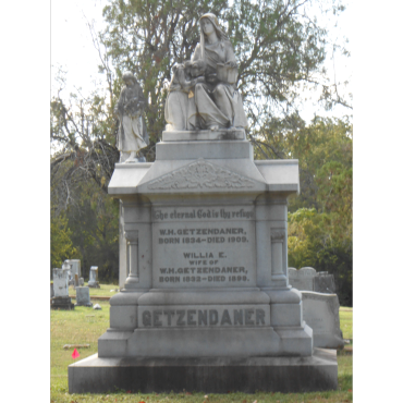 A large stone grave monument with statues in a cemetery.
