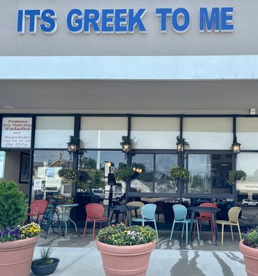 Front of a restaurant named 'Its Greek to Me' with outdoor seating.