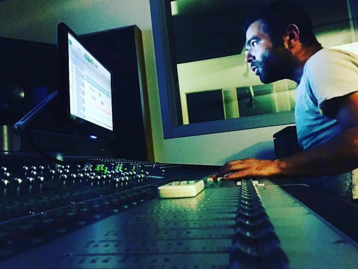 Basri Hayran working in studio behind the mixers table and DAW