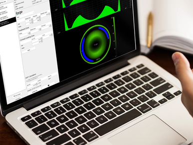 Laptop screen showing audio analysis software with green waveform and circular graph.