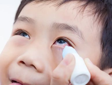 Child receiving eye drops for eye care.