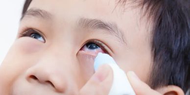 Child receiving eye drops for eye care.