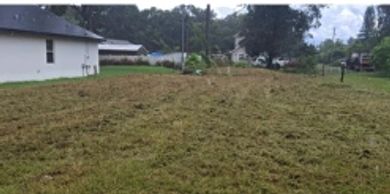 A freshly mowed grassy yard beside residential houses under a cloudy sky.