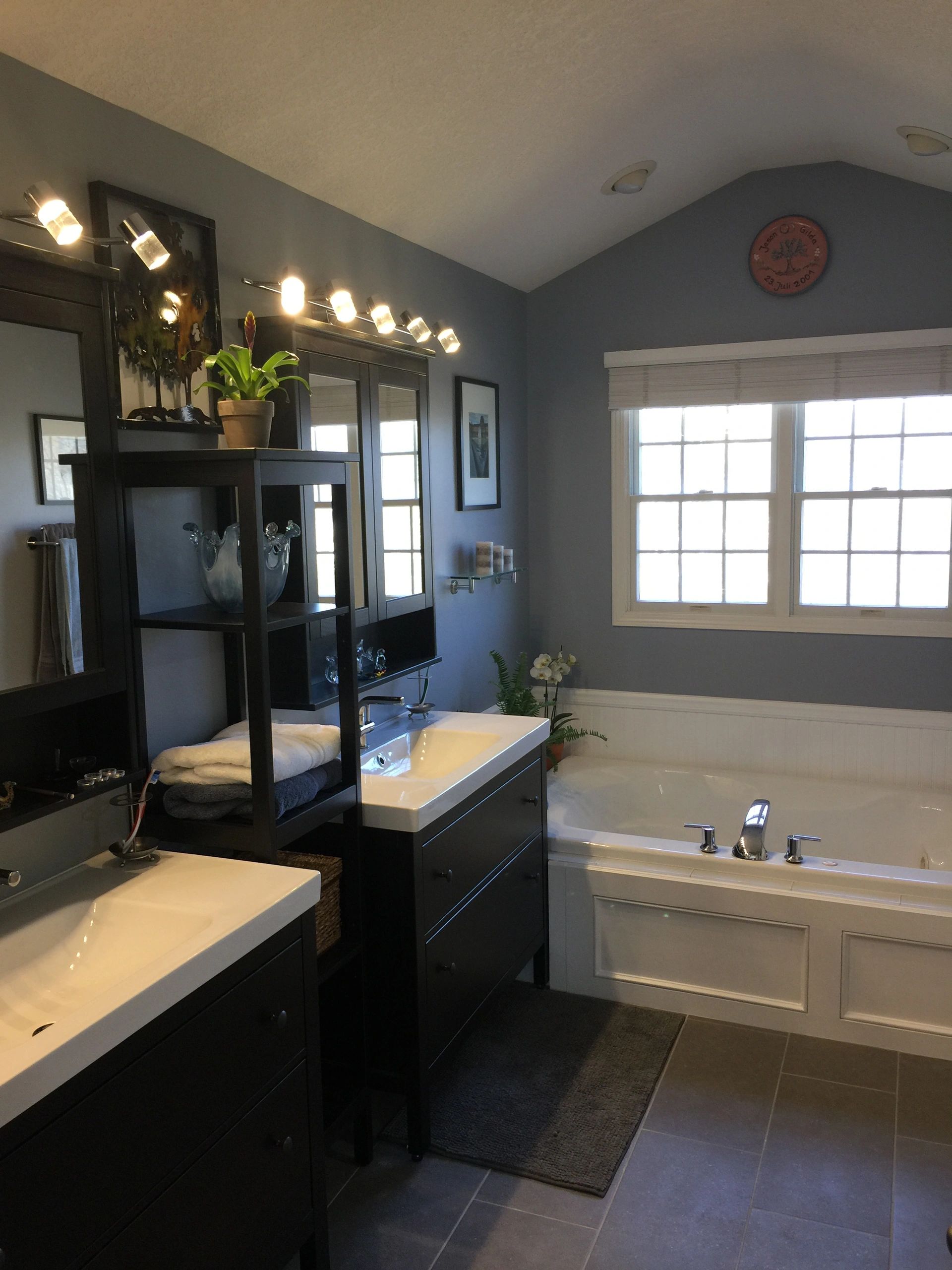 Well-lit modern bathroom with double sinks and bathtub.