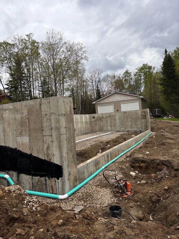 Close-up of a concrete foundation with new drainage tile and waterproofing system installed.