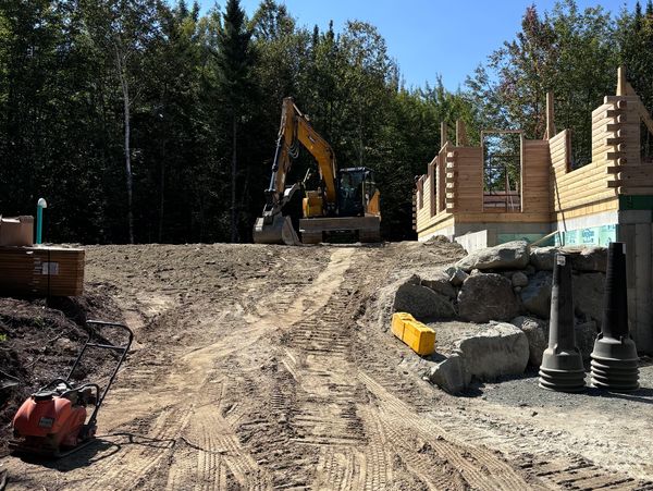 Excavation equipment preparing the ground for new log home construction. Full-service site work