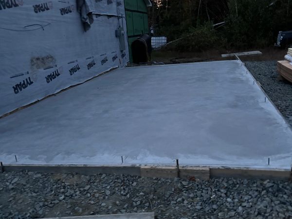 Freshly poured concrete slab adjacent to a residential structure. Expert work by Swallow & Sons