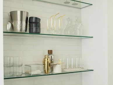Modern glass shelves display barware and glassware in a minimalist kitchen.