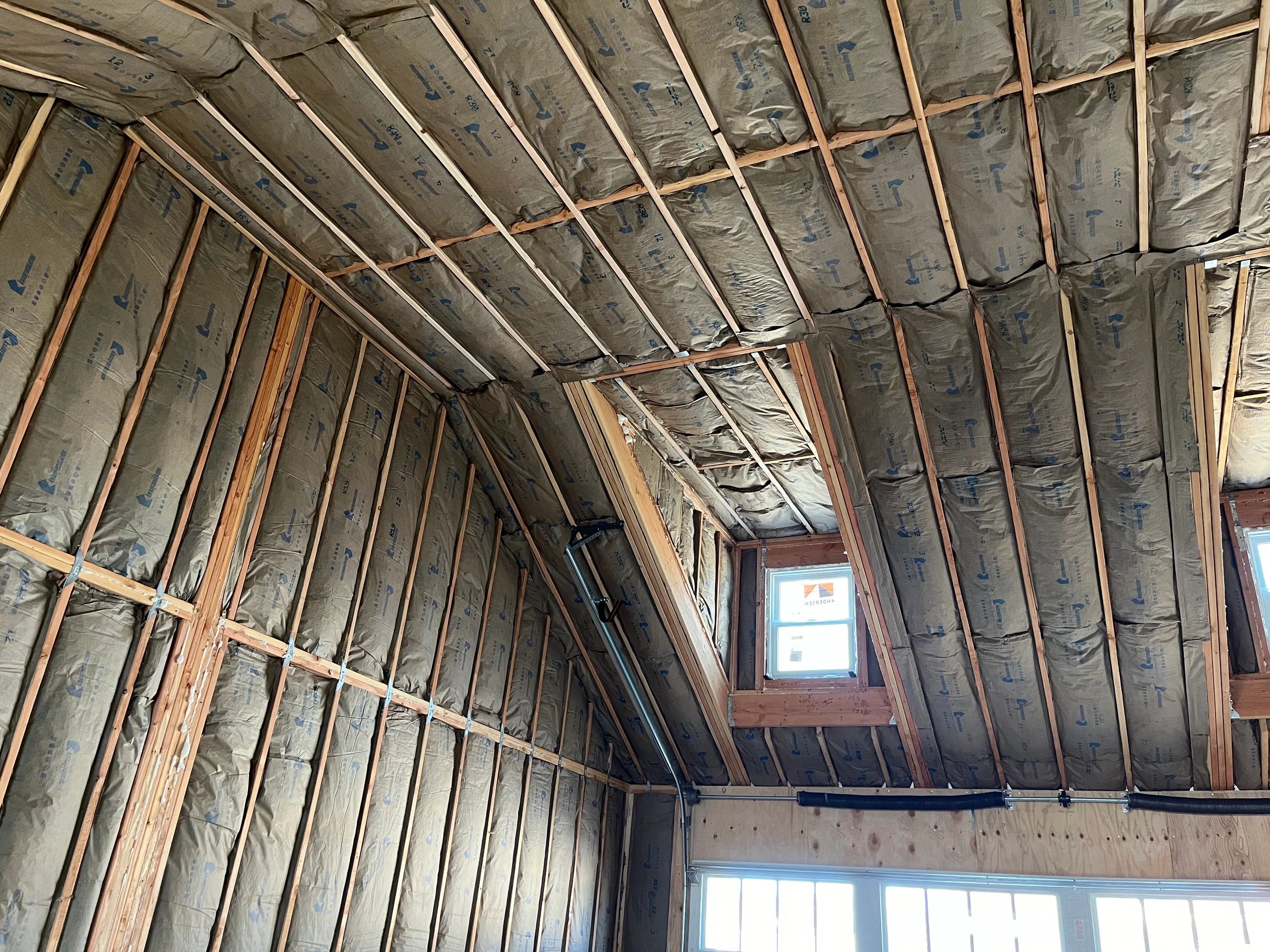 Insulated attic with wooden framing and windows.