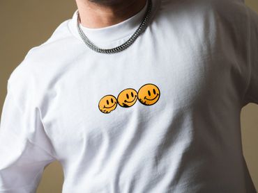 White shirt with three yellow smiley faces in a row.