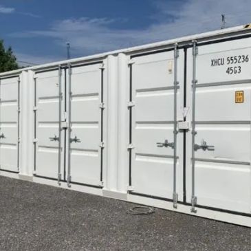 White shipping containers lined up outside under a blue sky.