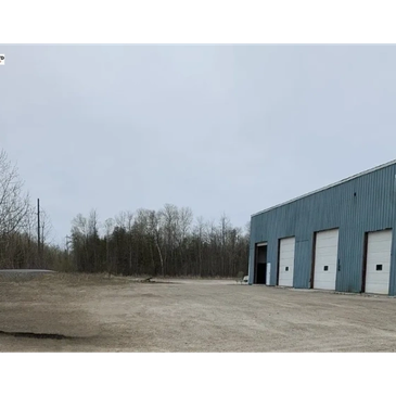 Empty industrial area with garage doors and overcast sky.