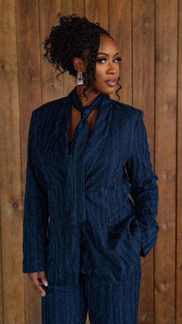 Woman in a blue suit with a wooden background.