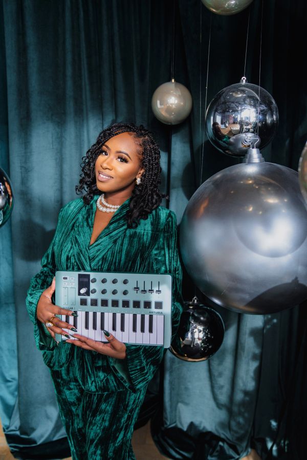 Woman in green velvet suit holding a small keyboard.