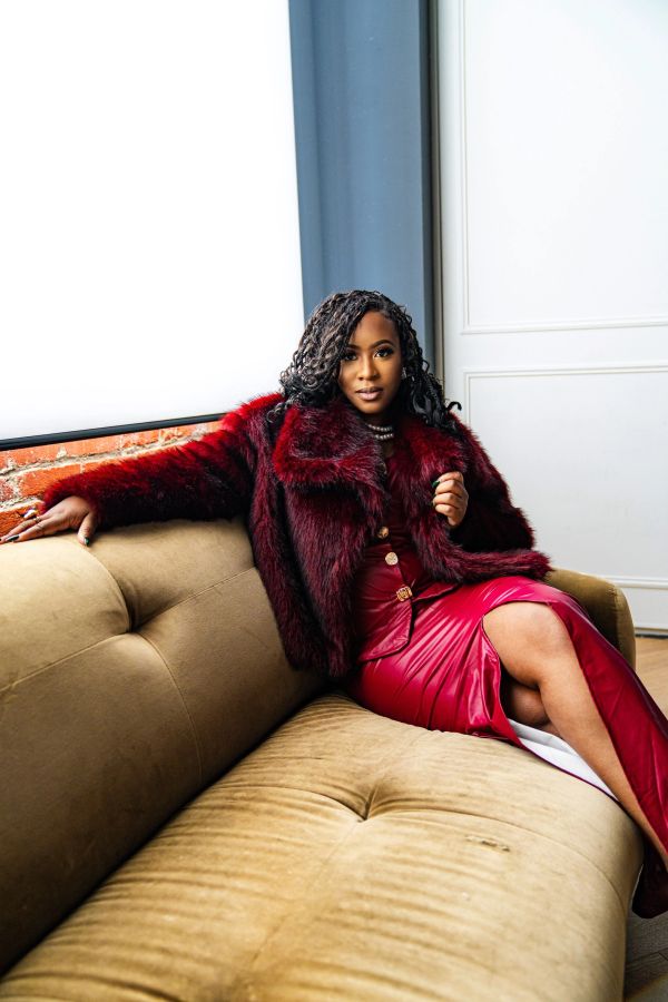 Woman in a red fur coat and skirt lounging on a couch.