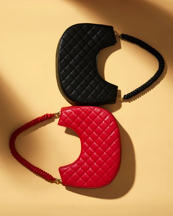 Two quilted handbags, one black and one red, on yellow surface.