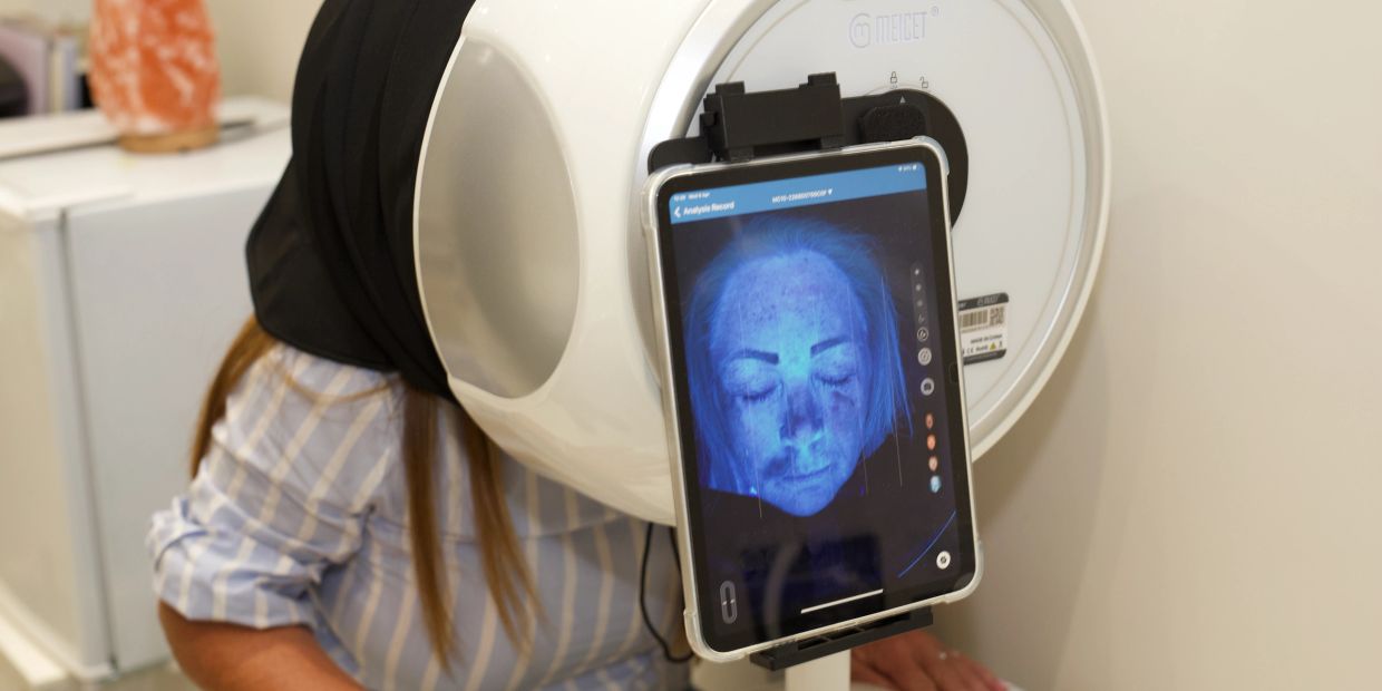 Woman using a facial skin analysis machine.