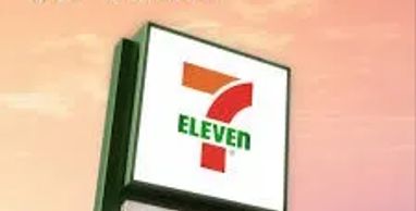 7-Eleven store sign against a sunset background.