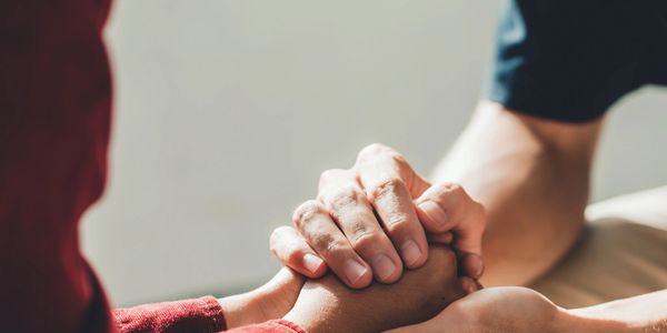 Two people holding hands in a comforting gesture.